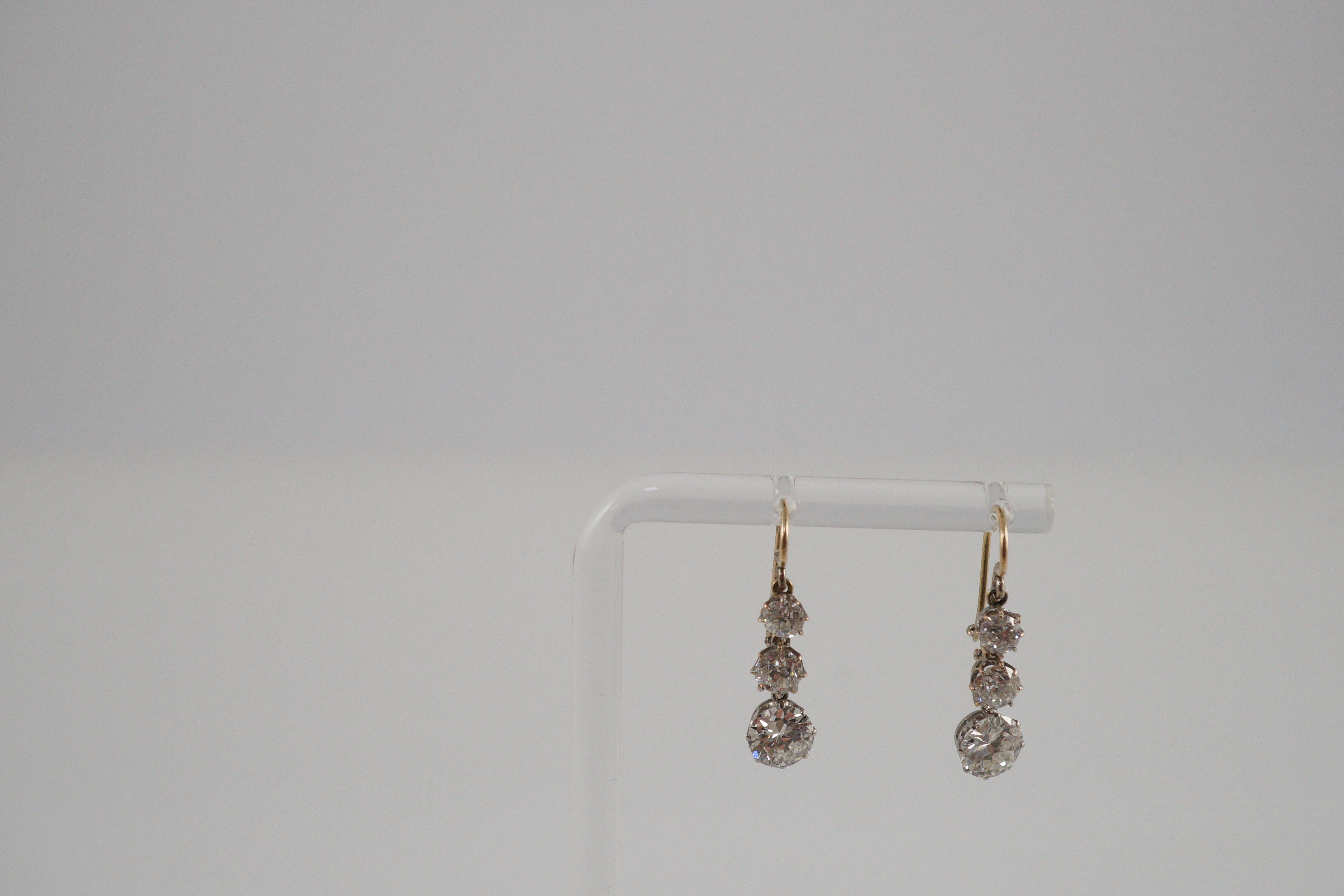 A pair of early to mid 20th century gold, platinum and graduated three stone diamond set drop earrings